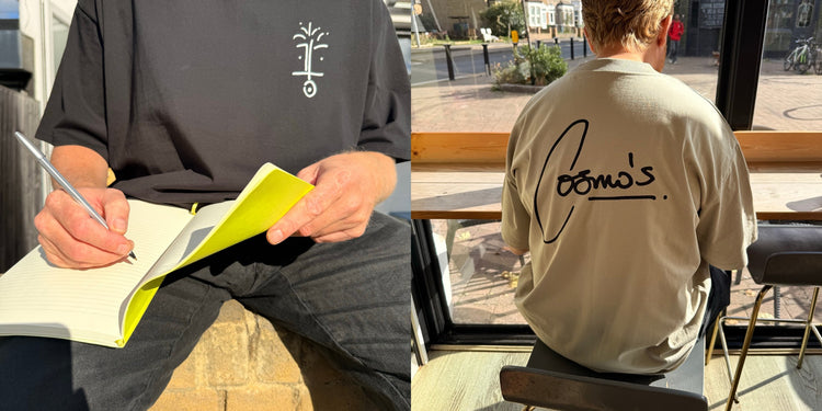 drawing in a yellow notebook in a black cosmo’s tee, beside the signature on the back of a stone tee in a café